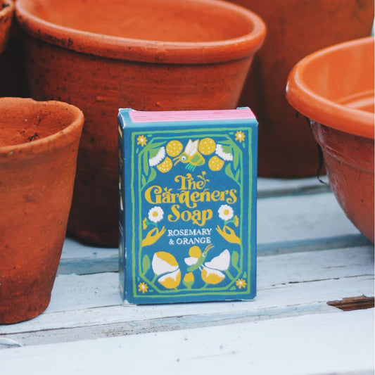Box of 'The Gardener's Soap' with terracotta pots on a wooden surface